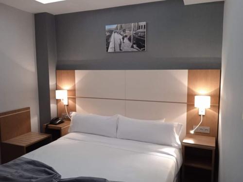 a bedroom with a white bed and two lamps at El Ghanami Hotel in Alger