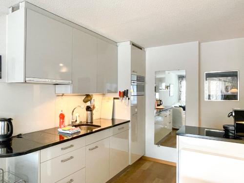 a kitchen with white cabinets and a sink at Eiger Residence in Wengen