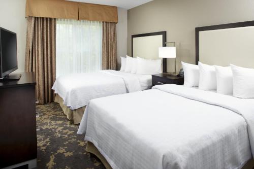 a hotel room with two beds and a flat screen tv at Trellis Lake Pointe in Charlotte