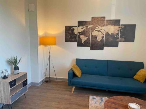 uma sala de estar com um sofá azul e um mapa do mundo em T2 4 pers face gare SNCF Appart Hotel le Cygne 4 em Bourges