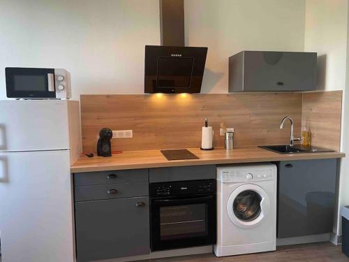 uma cozinha com uma máquina de lavar roupa e um lavatório em T2 4 pers face gare SNCF Appart Hotel le Cygne 4 em Bourges