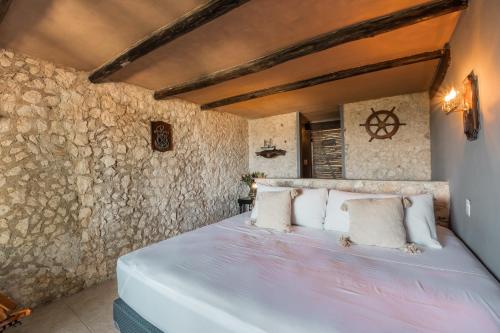 a bedroom with a large bed in a stone wall at Playa Esperanza Tulum in Tulum