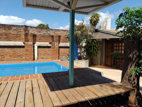 a swimming pool with a wooden deck and an umbrella at La Cascada in Posadas