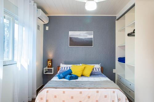 a bedroom with a bed with yellow and blue pillows at Residencial Paraíso da Gamboa in Garopaba