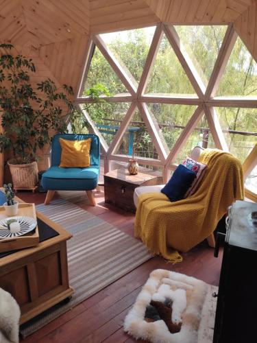 ein Wohnzimmer mit einem Sofa, Stühlen und einem Fenster in der Unterkunft Glamping Cantabria in Tunja