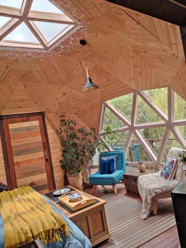 a living room with a wooden ceiling with windows at Glamping Cantabria in Tunja