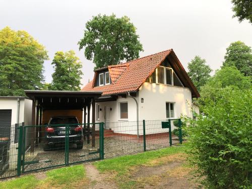 a white house with a red roof and a fence at Ferienhaus direkt an der Spree mit Whirlpool und Sauna in Berlin