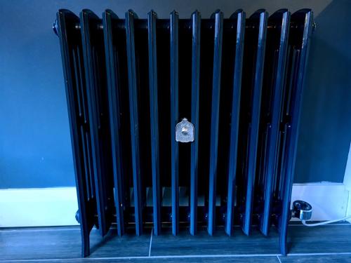a black radiator in a room next to a wall at BELFAST COSY CABIN in Belfast
