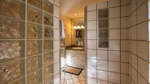 a bathroom with a tiled wall and a sink at Beautiful 2 Bedroom Oceanview Condo at Maui Kamaole Located at South End of Kihei Adjacent to Wailea Traditional Hawaiian Style in Wailea