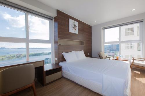 1 dormitorio con cama blanca y ventanas grandes en Chuỗi căn hộ Minh Phúc homestay Hạ Long en Ha Long