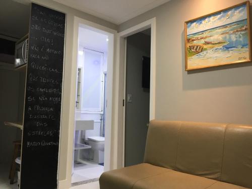 a living room with a couch and a chalkboard on the wall at Chalé em frente à Praia in Salvador