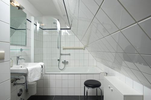 een badkamer met een bad, een wastafel en een kruk bij Witt Hingst App 10 in Tinnum