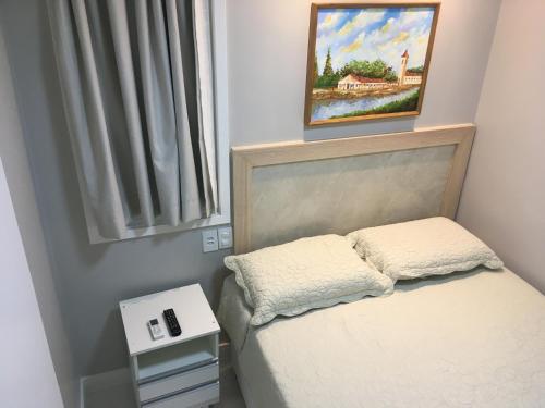 un pequeño dormitorio con una cama y una pintura en la pared en Chalé em frente à Praia, en Salvador