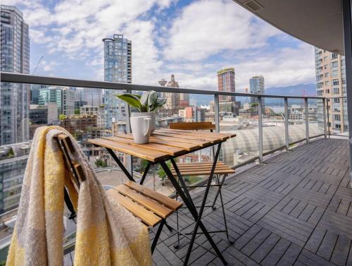 a balcony with a wooden table and a potted plant at Downtown King Suite-Surround Views-Pool/Gym/Parkng in Vancouver