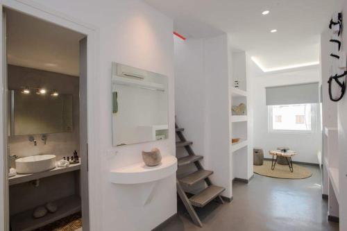a white bathroom with a sink and a mirror at Jonaz Rooms & Suites in Mikonos