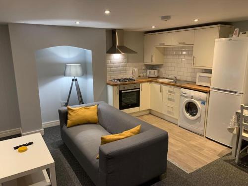 ein Wohnzimmer mit einem Sofa und einer Küche in der Unterkunft Fantastic 1 Bedroom Basement flat with free parking in Sale