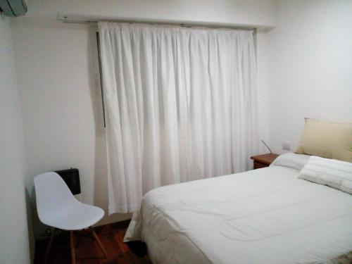 a bedroom with a white bed and a white chair at Lourdes in Rosario