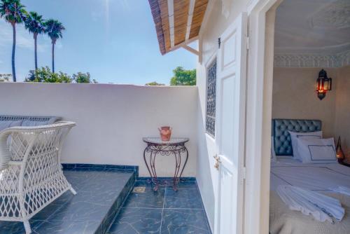 een veranda met een bed, een tafel en een stoel bij Samira Group & Spa in Marrakesh