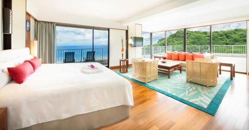 Hotel Nikko Guam في تومون: غرفة نوم بسرير كبير وغرفة معيشة