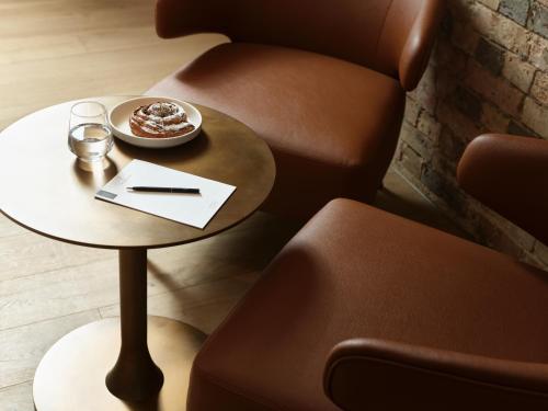 a table and a chair with a plate of food on it at The Porter House Hotel Sydney - MGallery in Sydney