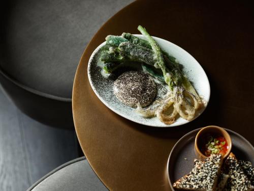a plate of food with broccoli on a table at The Porter House Hotel Sydney - MGallery in Sydney