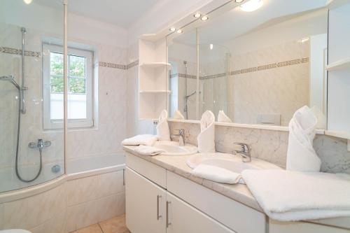 ein Bad mit 2 Waschbecken, einer Dusche und einem Spiegel in der Unterkunft Kate Kleinod in Westerland