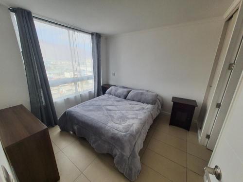 a bedroom with a bed and a large window at Edificio Bulnes Iquique in Iquique