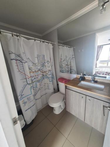 a bathroom with a toilet and a sink and a shower curtain at Edificio Bulnes Iquique in Iquique