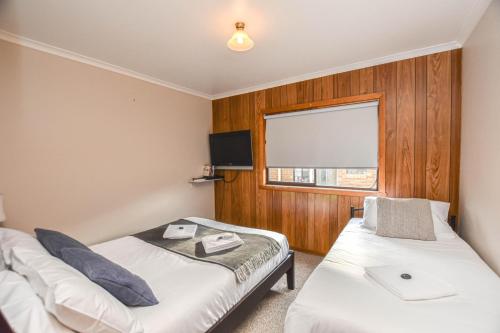 a room with two beds and a flat screen tv at Jamieson Cottage in Myrtleford