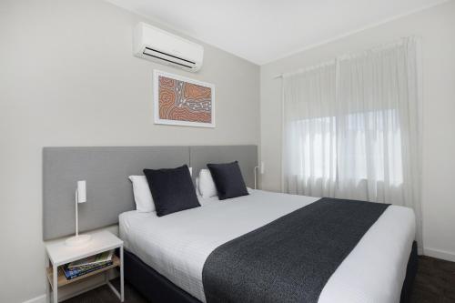 a bedroom with a large white bed and a window at Quest Mawson Lakes in Adelaide