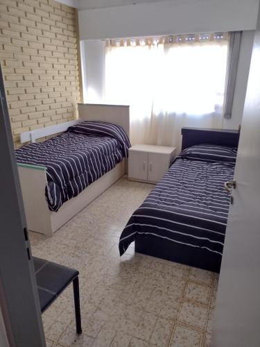 a bedroom with two beds and a window at Angeles del Limay in Cipolletti