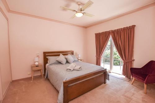 sypialnia z łóżkiem z wentylatorem sufitowym i oknem w obiekcie Karinya Cottage w mieście Myrtleford