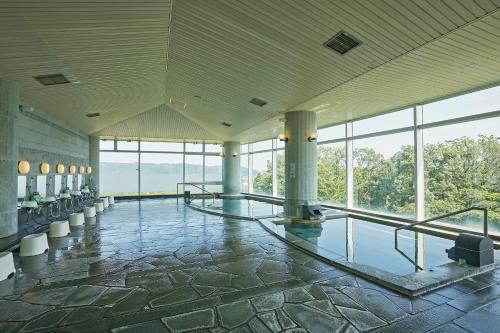 a large room with a pool in a building with windows at KAMENOI HOTEL Fukui in Fukui
