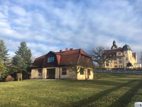 a house in a field with a building in the background at Ferienhaus Monika in Wendorf im Bernstein Resort in Wendorf