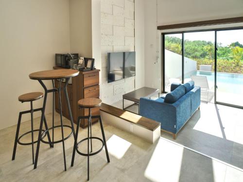 a living room with a couch and a table and stools at ADANRESORT LANA Villa Suite in Motobu