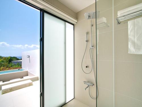 un bagno con doccia con porta in vetro di ADANRESORT LANA Villa Suite a Motobu