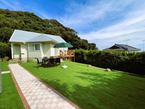a house with a lawn with a table and an umbrella at Tsunore51 in Kashima