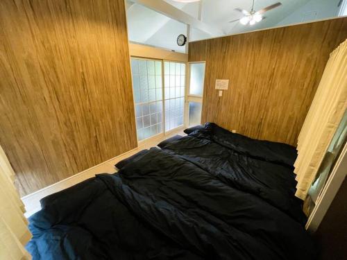 un letto in una camera da letto con parete in legno di Tsunore51 a Kashima