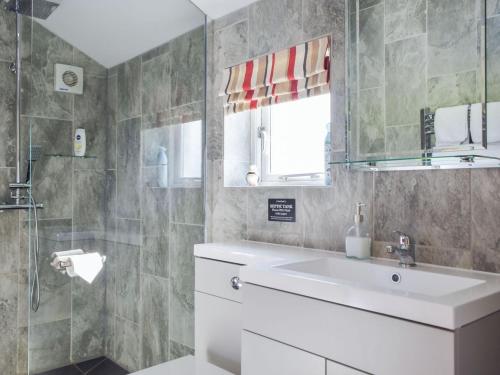 uma casa de banho com um lavatório branco e um chuveiro em Y Bwthyn em Llanwinio