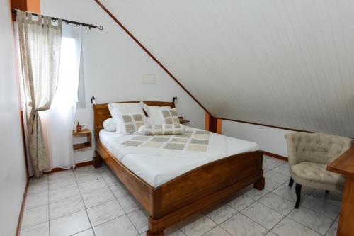 a bedroom with a bed and a chair and a window at ORKY-MEL in Petite Île