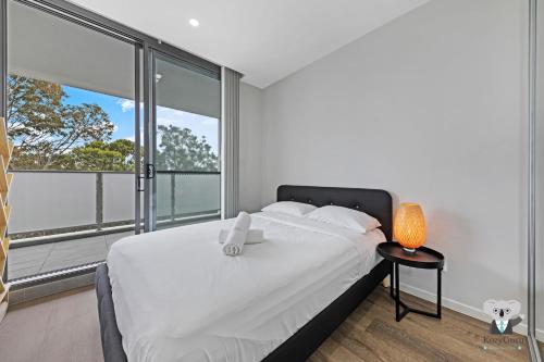 a bedroom with a white bed and a large window at KozyGuru | Wentworthville | Kozy Style 2 Bed 2 Bath APT + Free Parking in Wentworthville