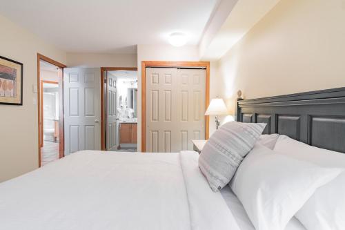 a bedroom with a white bed with a black headboard at The best ski in ski out two bedroom condo at Aspens in Whistler