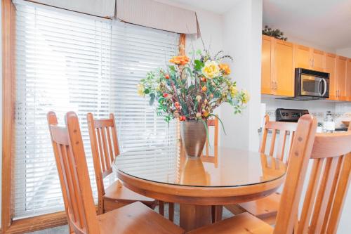 a dining room table with a vase of flowers on it at The best ski in ski out two bedroom condo at Aspens in Whistler
