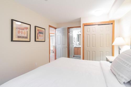 a white bedroom with a white bed and a door at The best ski in ski out two bedroom condo at Aspens in Whistler