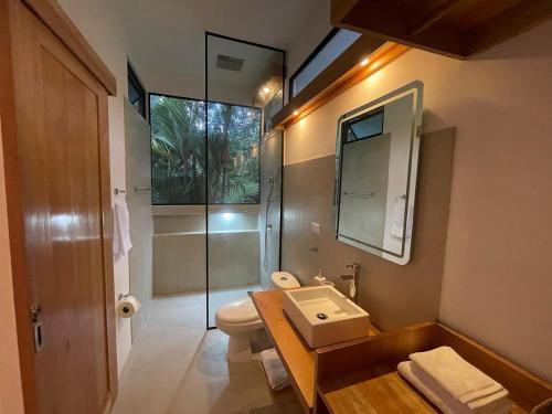 a bathroom with a toilet and a sink and a shower at Caribbean Irie - charming, luxurious bungalow in nature with AC & fiber optic wifi in Puerto Viejo