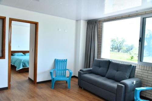 1 dormitorio y sala de estar con sofá y silla. en Cucuate Hospedaje, en Choachí