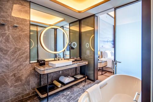 a bathroom with a tub and a sink and a mirror at Pullman Suzhou Taicang in Taicang