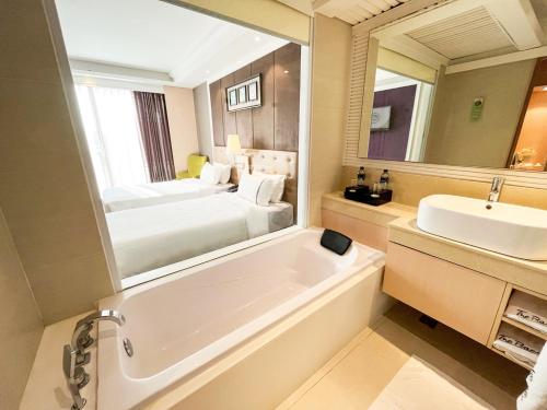 a bathroom with a tub and a sink and a bed at The Bazaar Hotel Bangkok in Bangkok