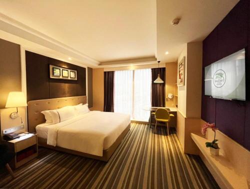 a hotel room with a bed and a television at The Bazaar Hotel Bangkok in Bangkok