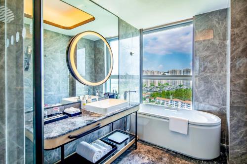 a bathroom with a tub and a sink and a mirror at Pullman Suzhou Taicang in Taicang